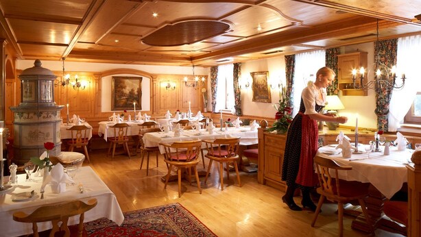 A traditional dining room with wooden furniture, white tablecloths, and a central chandelier. - Hotel Ochsen (Stuttgart)