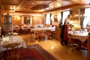 Une salle à manger traditionnelle, avec des meubles en bois, des nappes blanches et un lustre central.