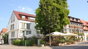 A street view with a tree-lined sidewalk, a café with outdoor seating, and traditional European architecture. - Hotel Ochsen (Stuttgart)