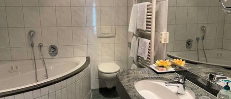 A modern bathroom with a freestanding bathtub, a toilet, and a sink with a granite countertop.