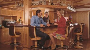 A wooden interior with a bar area, wooden bar stools, and a kitchen in the background. - Hotel Ochsen (Stuttgart)