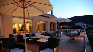 An outdoor patio area with wicker furniture, umbrellas, and a view of the surrounding landscape. - Isola Verde (Marciana Marina)
