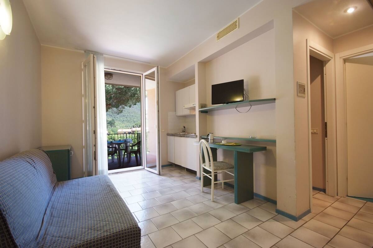 A compact room with a bed, a desk, a chair, and a television.