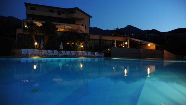 A swimming pool with lounge chairs and a building in the background. - Isola Verde (Marciana Marina)