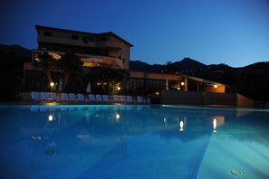 A swimming pool with lounge chairs and a building in the background. - Isola Verde (Marciana Marina)