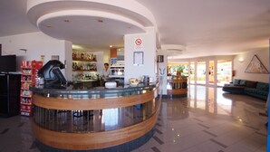 A hotel lobby with a curved reception desk, a bar area, and a seating area with a sofa. - Isola Verde (Marciana Marina)