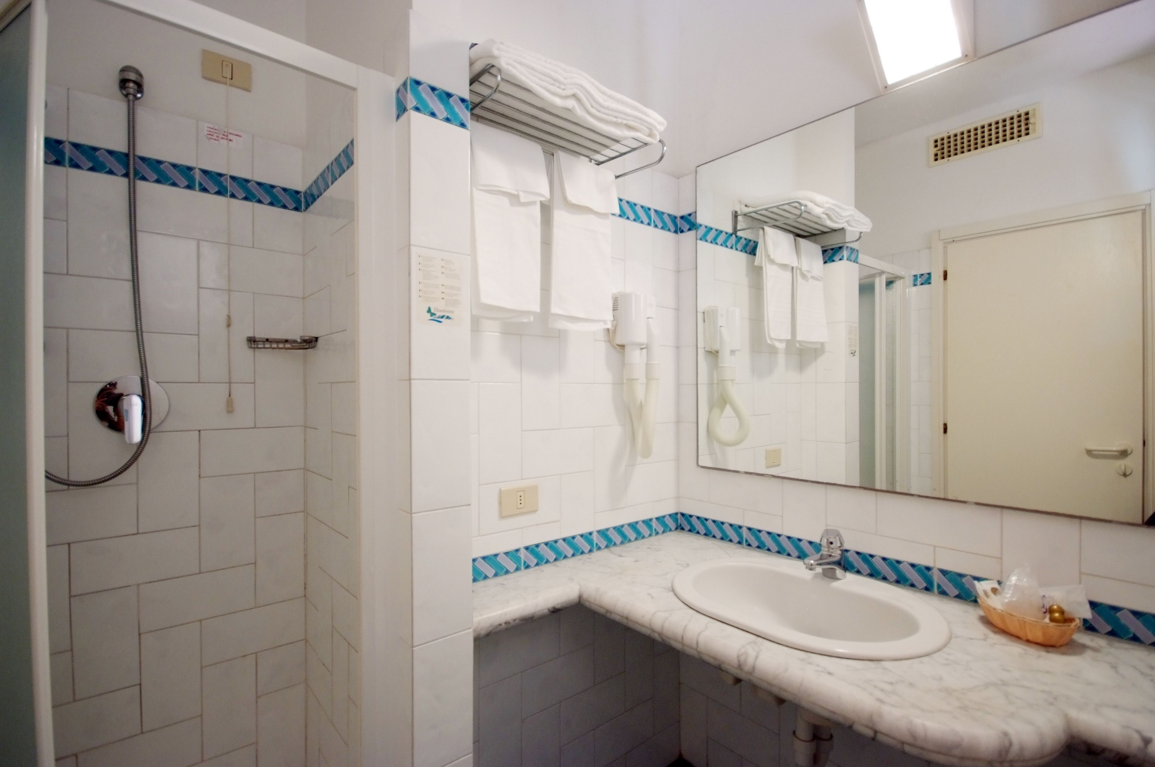 A bathroom with a shower, a sink, and a mirror.