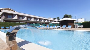 Una piscina con sillas de descanso y un edificio al fondo.