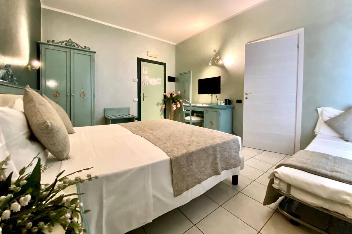 A bedroom with a bed, a desk, a wardrobe, and a door.