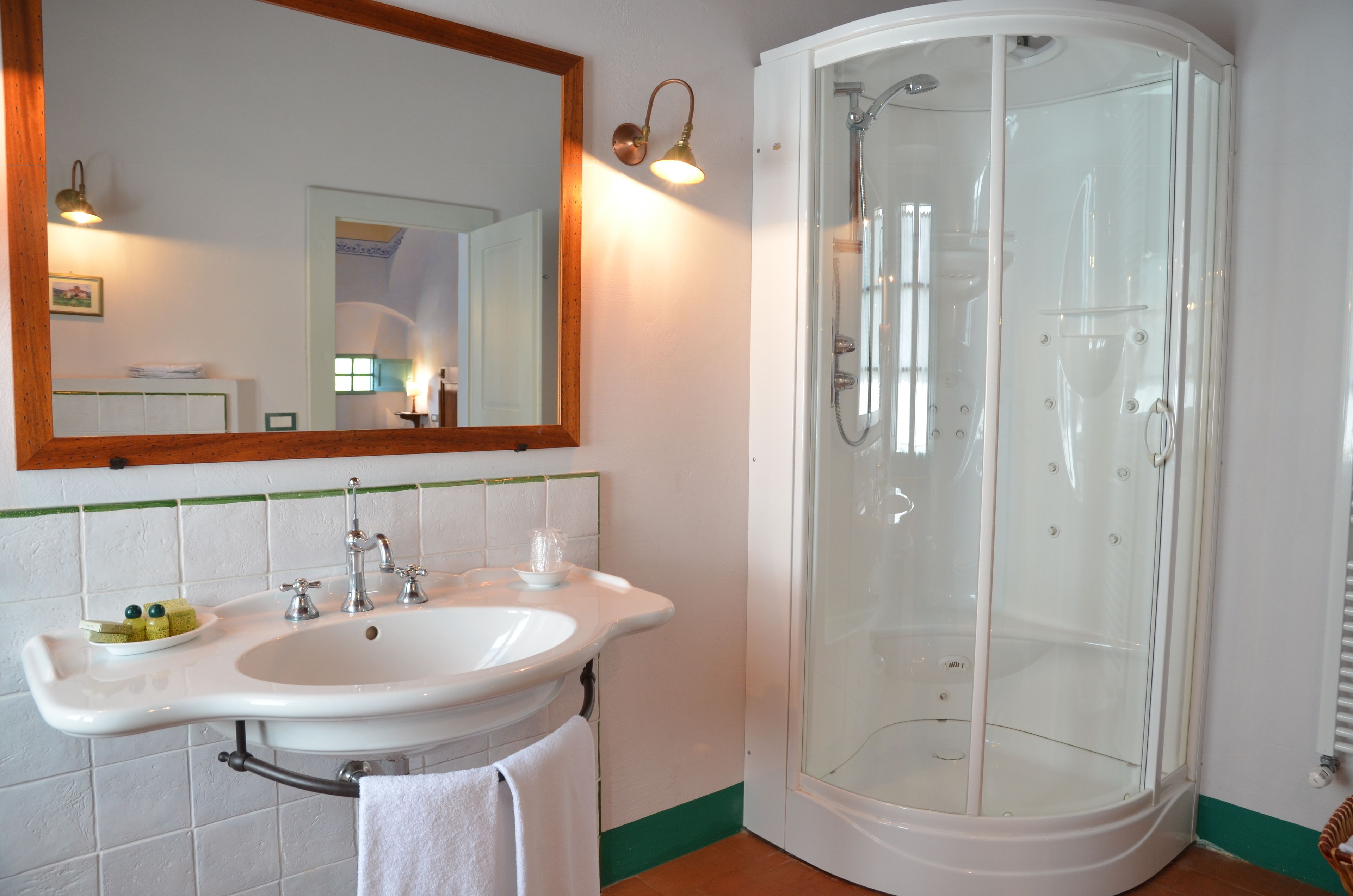 Ein Badezimmer mit einem weißen Waschbecken, einem Spiegel und einer Glasdusche.
