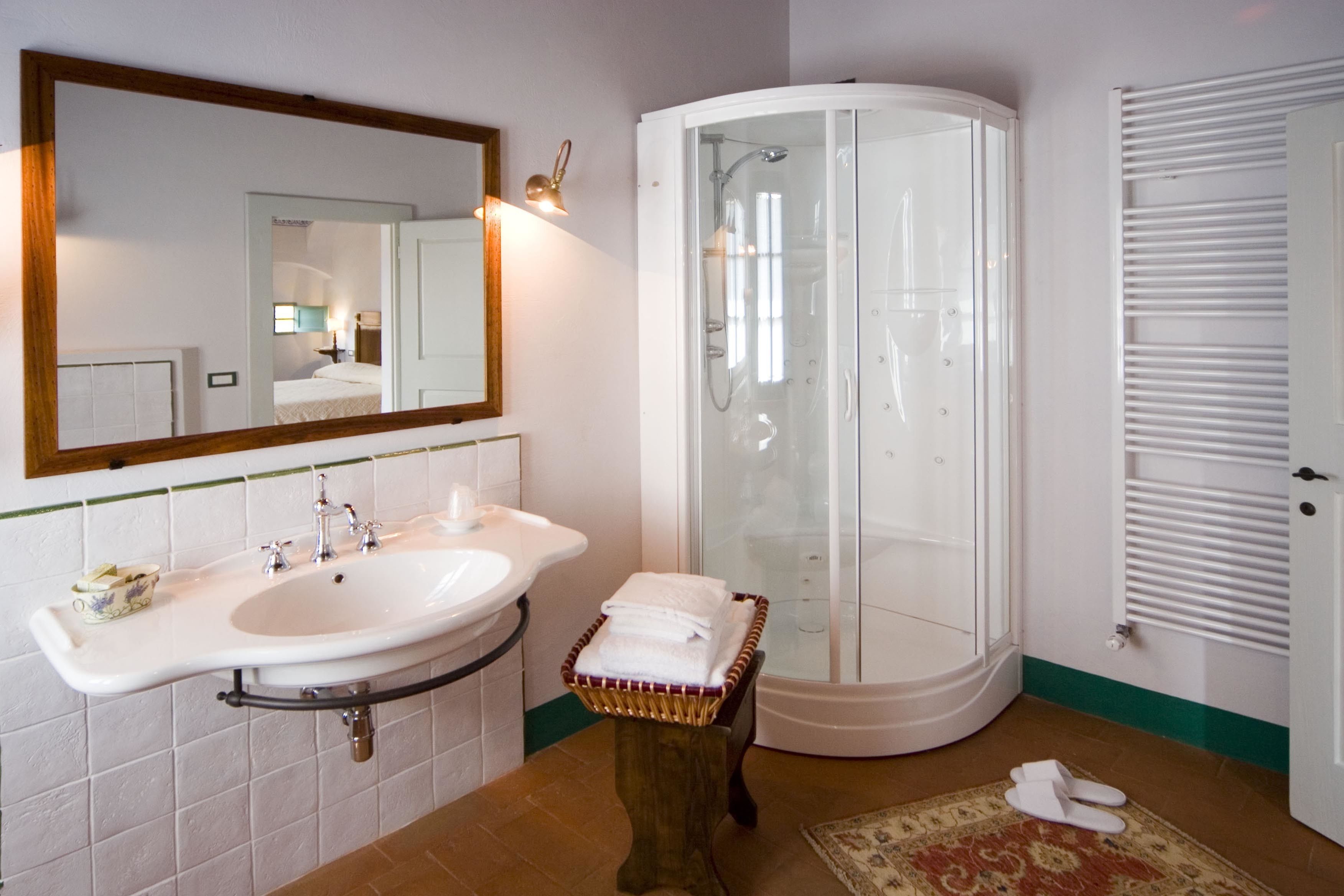 A bathroom with a double sink, a glass-enclosed shower, a mirror, and a towel rack.