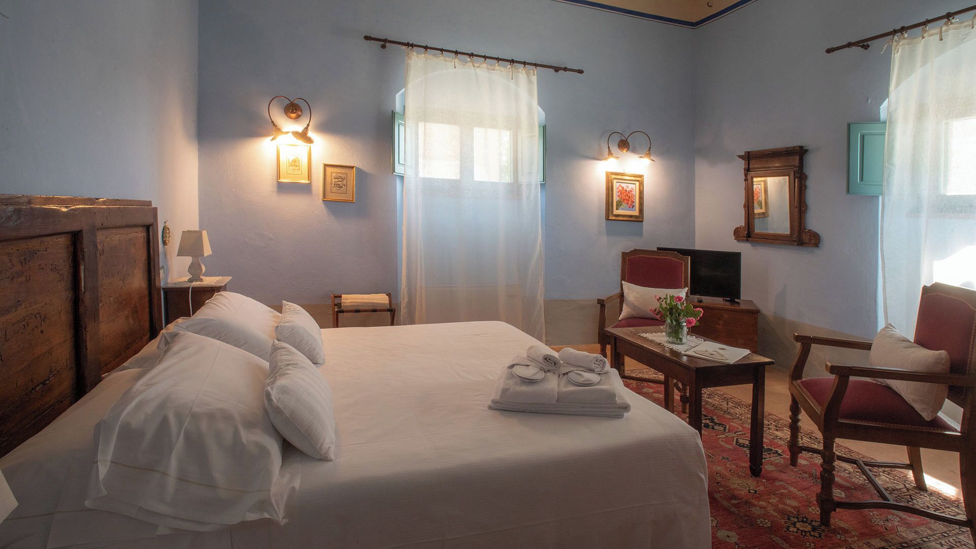 A hotel room with a large bed, a desk, a chair, and a television.