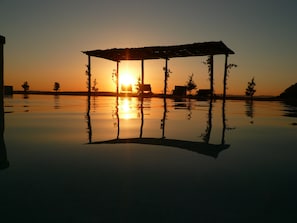 A tranquil sunset over a calm body of water with a gazebo structure in the foreground. - Cortona Resort - Le Terre Dei Cavalieri (Cortona)
