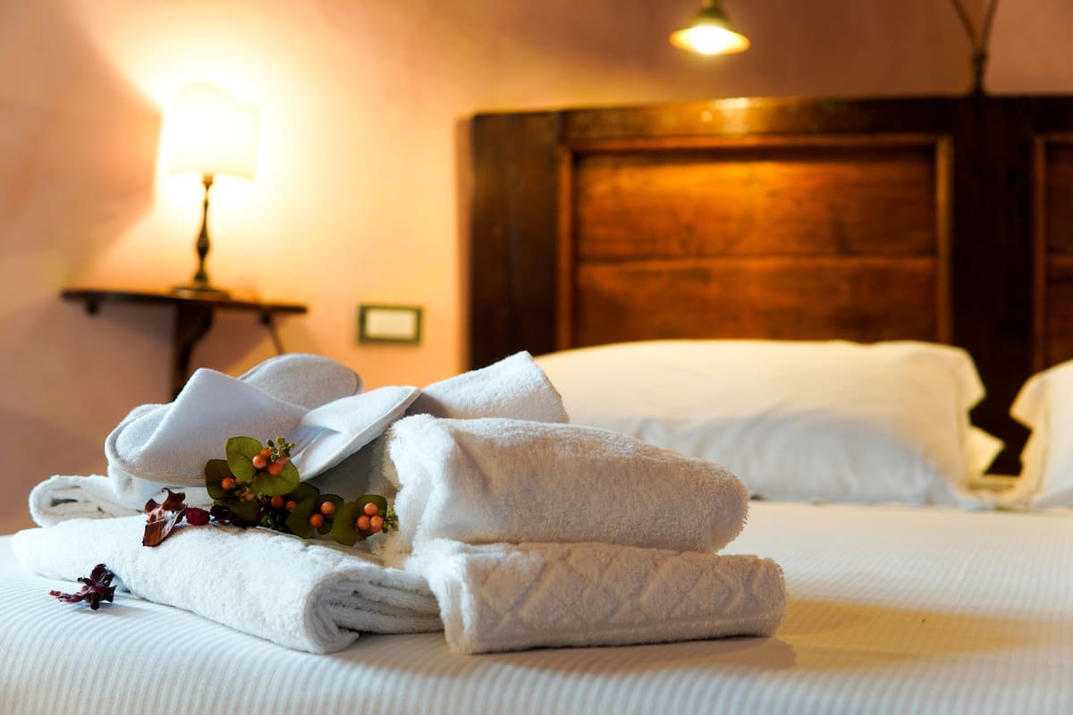 Una cama bien hecha con toallas dobladas y un arreglo decorativo de flores.