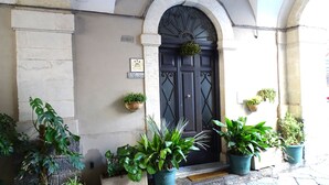A building entrance with a dark arched door, potted plants on either side, and a small sign above the door. - B&B Crociferi Catania (Catania)