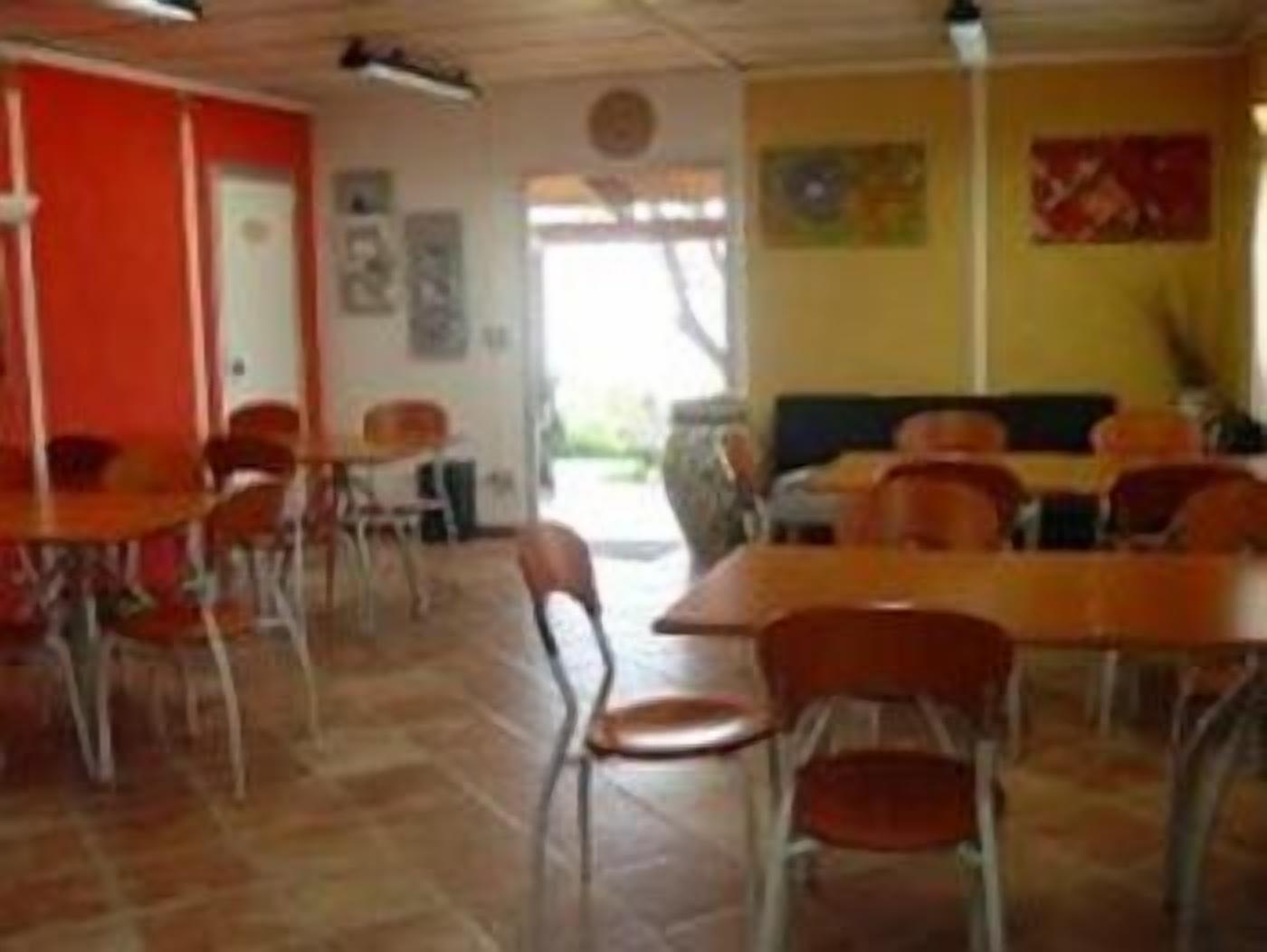 Un comedor con mesas y sillas, una pared roja y una puerta.