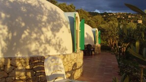 Un muro de piedra con una silla de plástico blanca y una mesa con azulejos.