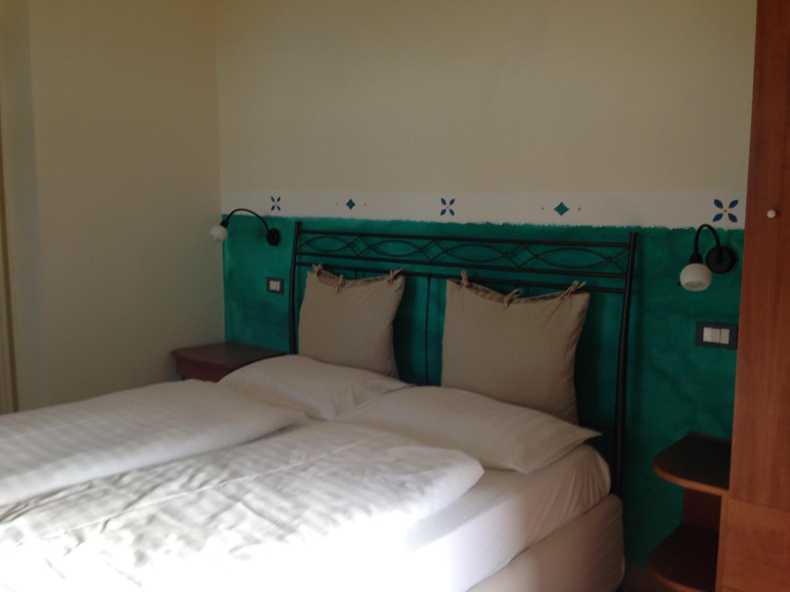 Ein Bett mit Kopfteil, zwei Nachttische und eine Wand mit Dekorationselementen.