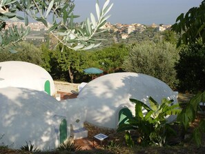 Vue d’une zone côtière avec des structures blanches en forme de dôme, probablement des logements, entourées de verdure et surplombant un paysage urbain.
