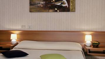 A neatly made bed with two pillows, a wall-mounted painting, and bedside lamps.