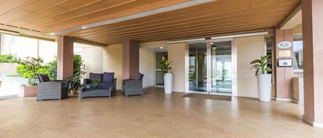 A spacious lobby with a wooden ceiling, comfortable seating, and potted plants.