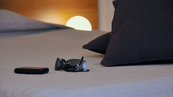 A bed with a pillow, a remote control, and a pair of sunglasses on it.