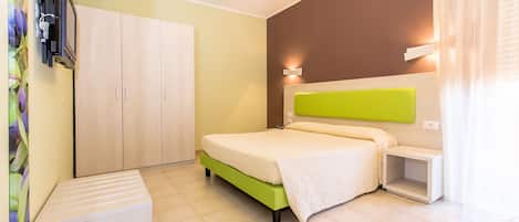 Un dormitorio con cama, armario, televisor y una mesita de noche pequeña.