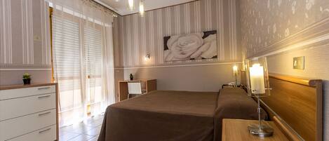 Un dormitorio con cama, mesita de noche, lámpara y una gran obra de arte floral en la pared.