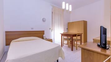Een hotelkamer met een bed, een bureau, een stoel, een televisie en een kledingkast.