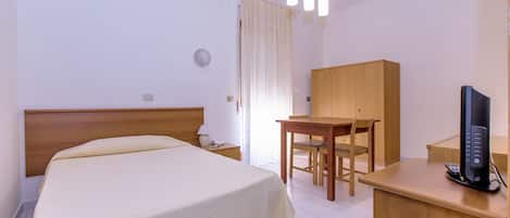 A hotel room with a bed, a desk, a chair, a television, and a wardrobe.