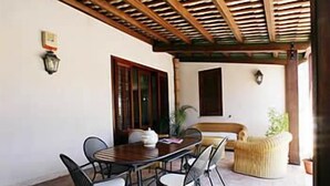 An outdoor patio with a wooden pergola, a dining table with chairs, and a sofa. - Borgo Pida (Misiliscemi)