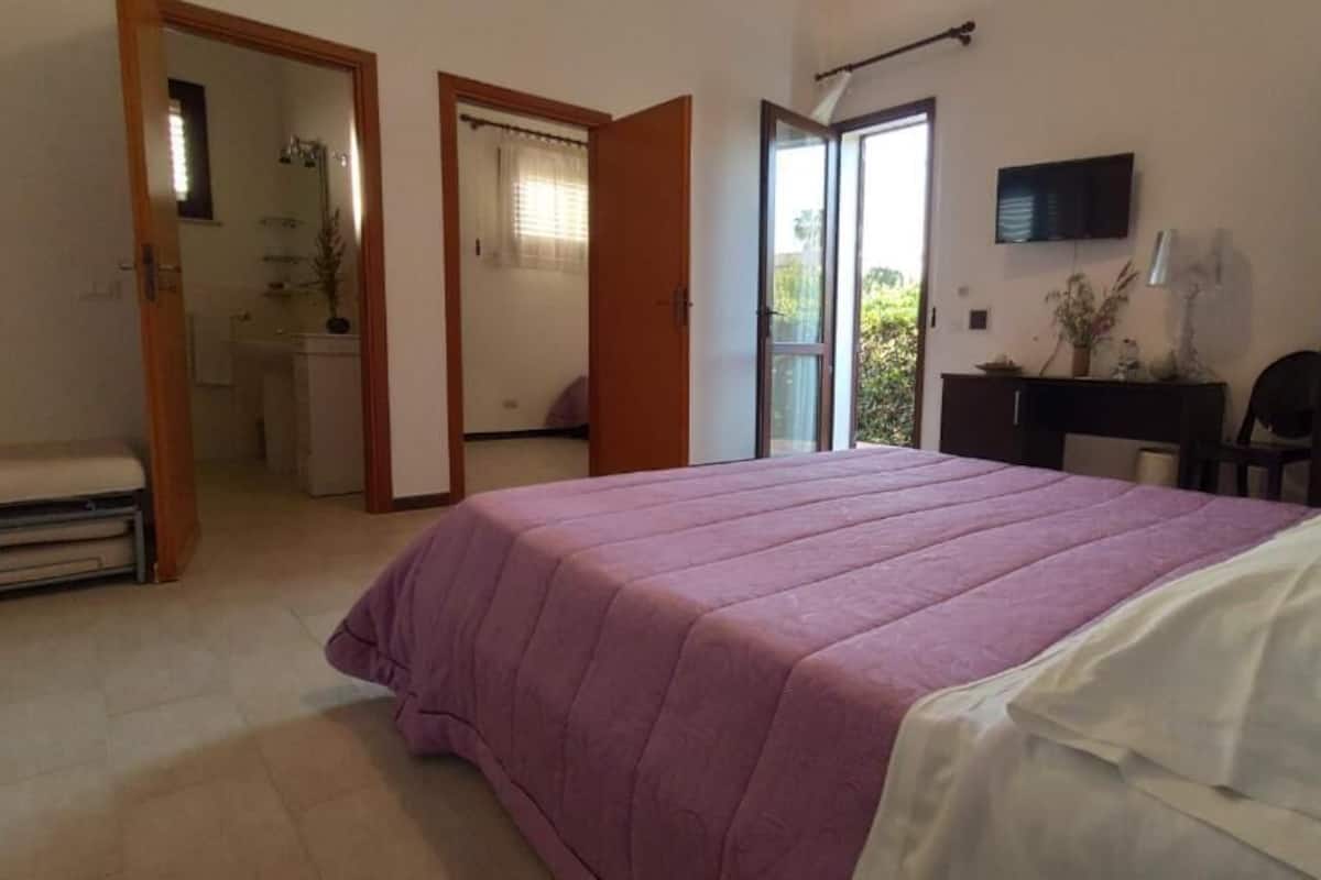 Una camera da letto con un letto, una scrivania e un televisore.