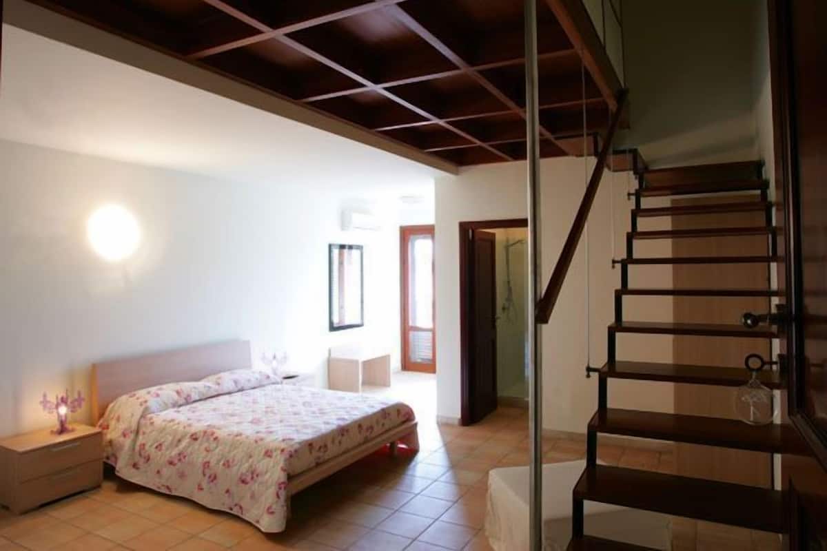 Una camera da letto con un letto, un comodino e una scala.