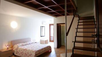 Un dormitorio con cama, mesita de noche y una escalera.