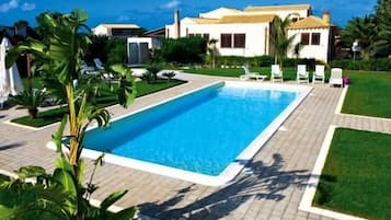 Una piscina al aire libre, camas de piscina gratis, sombrillas