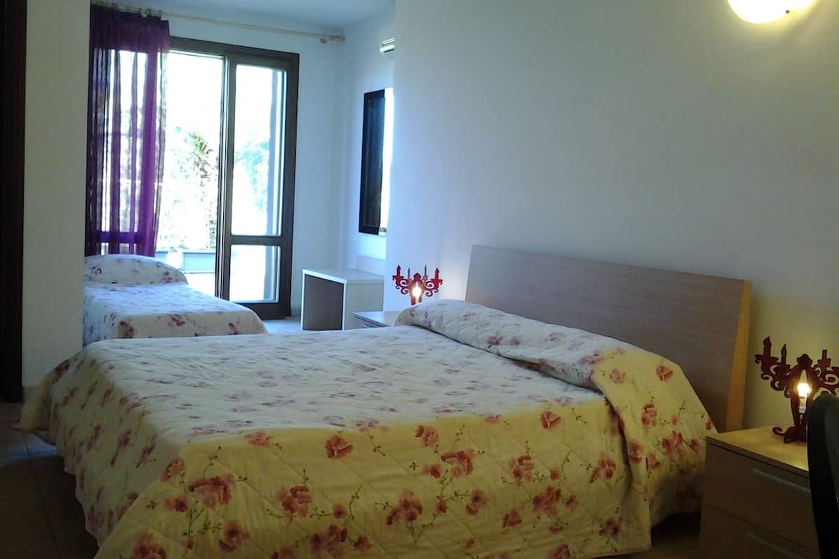 Una camera da letto con due letti, una scrivania e una finestra con tende.