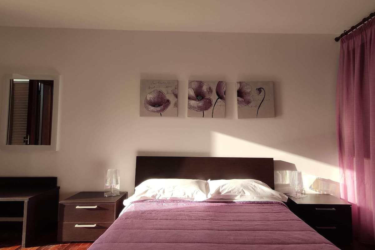 Una camera da letto con un letto, comodini, una scrivania e una finestra con persiane.