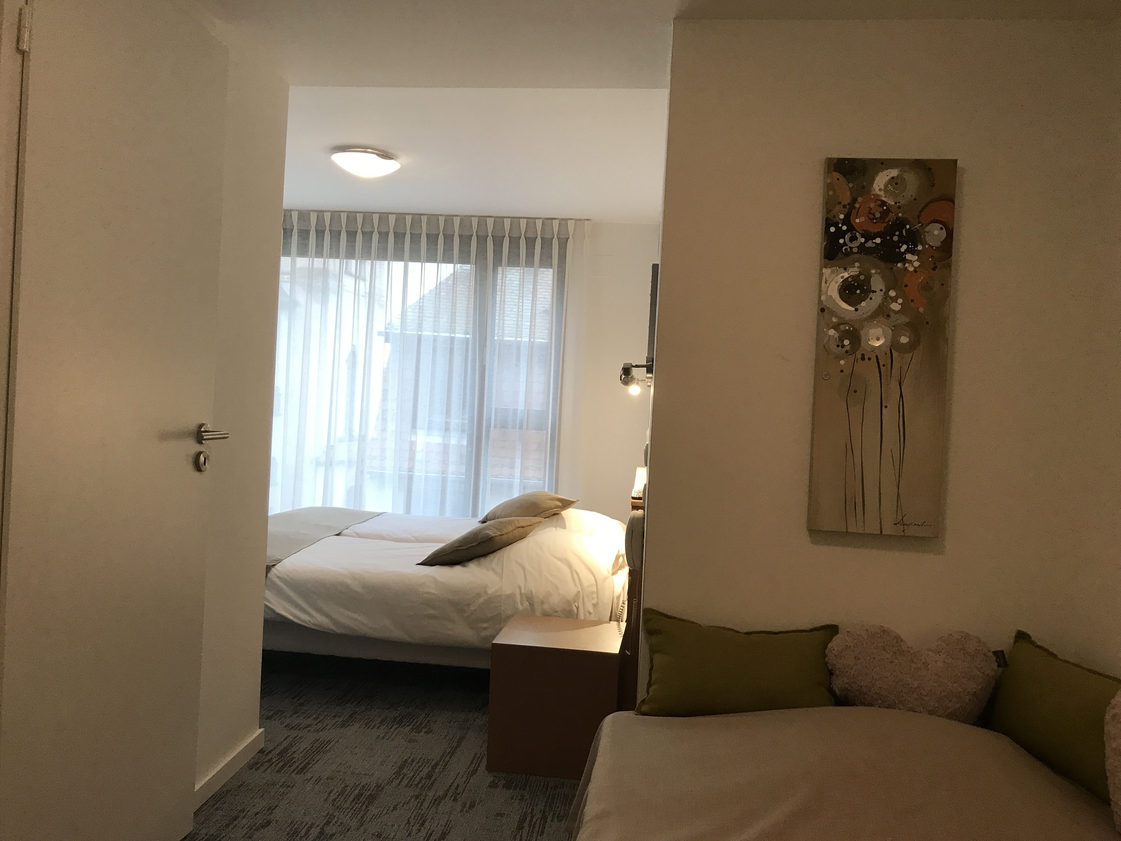 Ein Schlafzimmer mit einem Bett, einem Nachttisch, einer Lampe und einem Bild an der Wand.