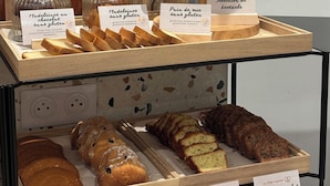 Mostrador de panadería con opciones sin gluten y de chocolate, que incluye pretzels, pan y pasteles.