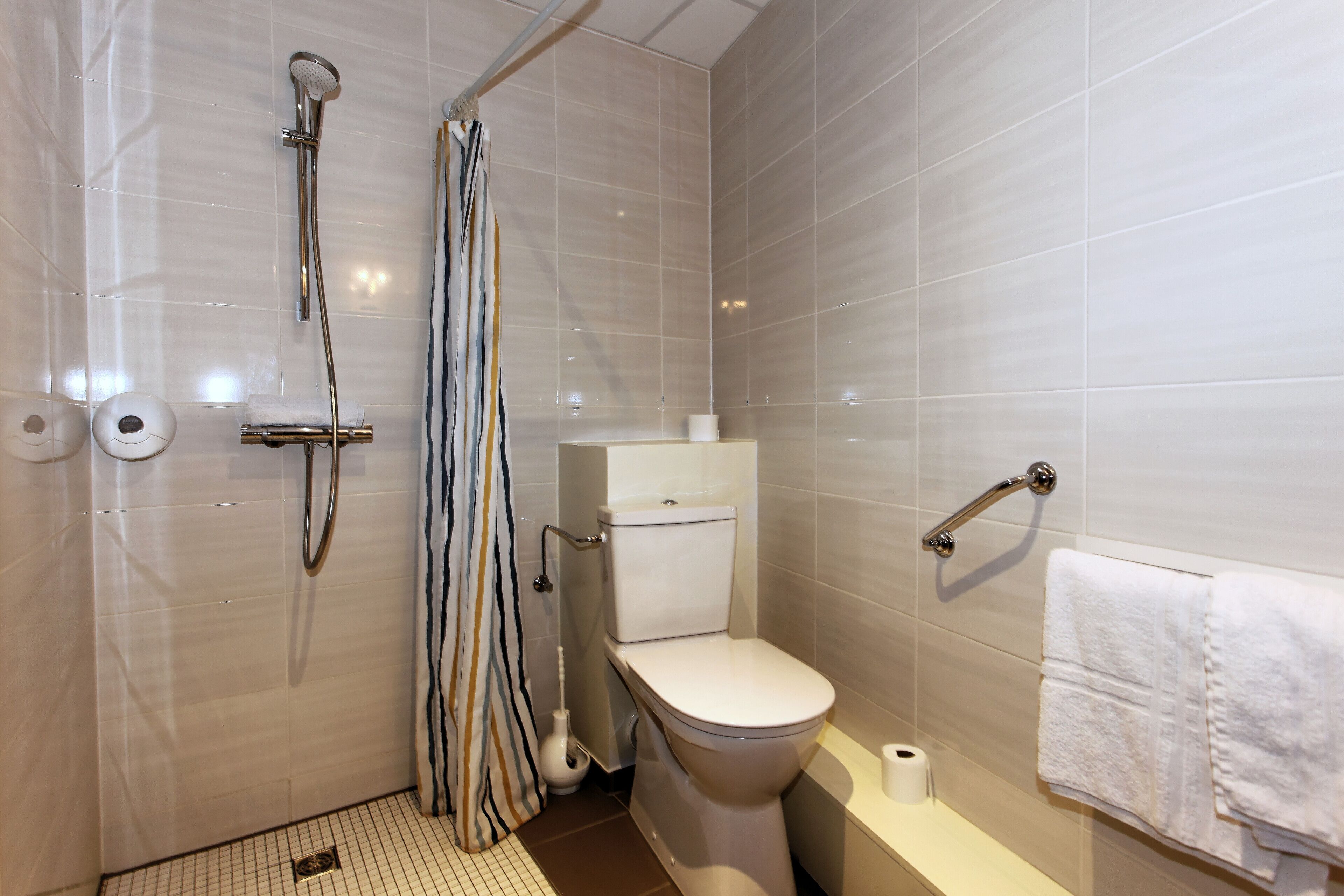 A modern bathroom with a shower, toilet, and a towel rack.