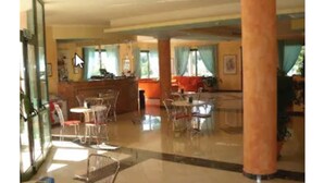 A spacious lobby with a reception desk, multiple seating areas, and large windows allowing natural light. - Hotel Baia Marina (Orosei)