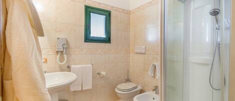 A bathroom with a sink, toilet, bidet, and a glass-enclosed shower.