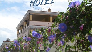 A hotel sign with a balcony and flowering vines in the foreground. - Hotel Baia Marina (Orosei)