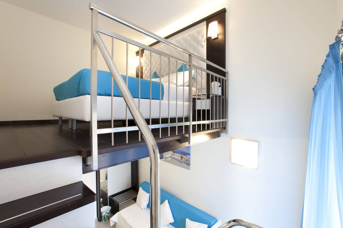 Una camera d'albergo con un letto a castello, una piccola scrivania e una scala.