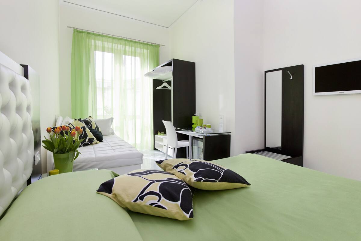 Una camera d'albergo moderna con un letto grande, una scrivania, un armadio e un angolo doccia.