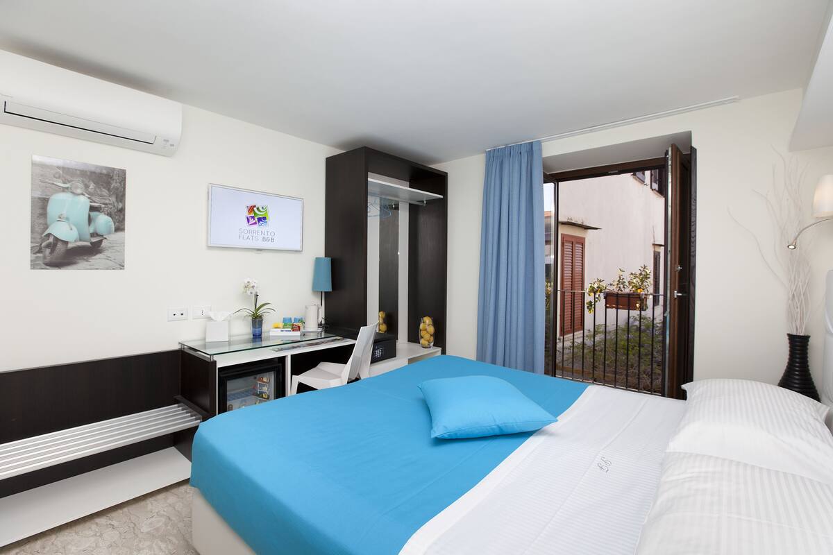 Camera d'albergo con un letto, una scrivania, una sedia, uno specchio e una finestra vista esterna.