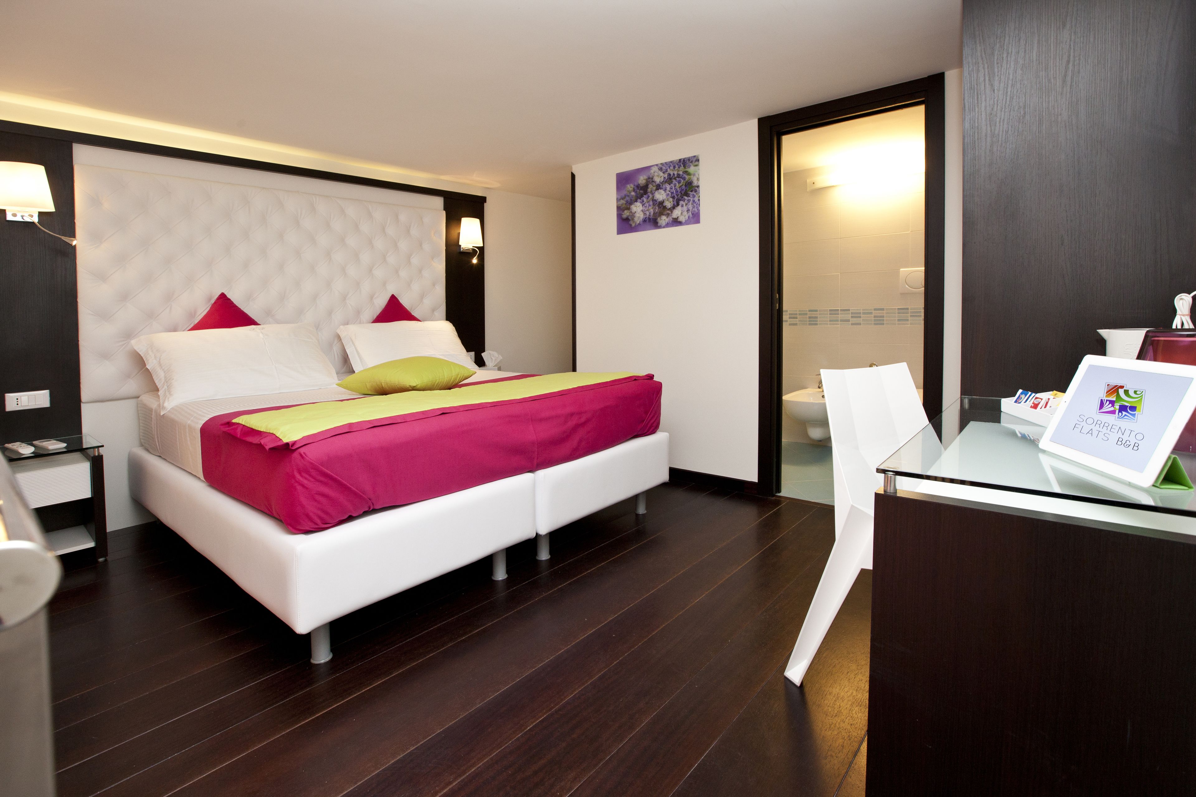 Una habitación de hotel moderna con una cama grande, un escritorio y un baño visible a través de una puerta abierta.