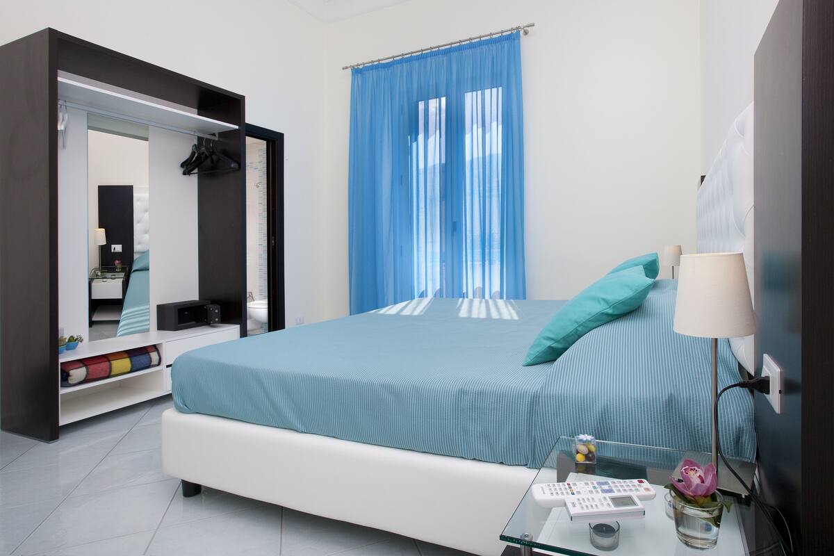 Una camera da letto moderna con un letto, un comodino, una lampada, uno specchio e un armadio.
