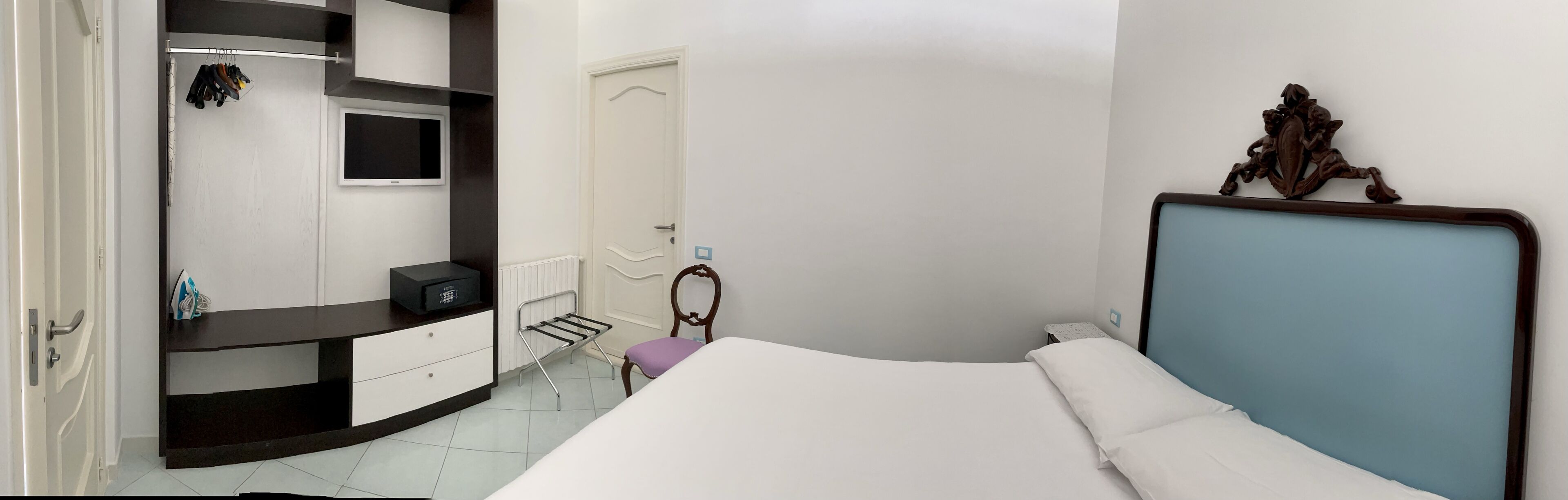 Een slaapkamer met een bed, een dressoir, een kaptafel, een spiegel en een deur.