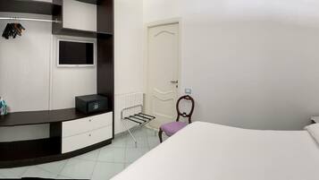 Een slaapkamer met een bed, een dressoir, een kaptafel, een spiegel en een deur.